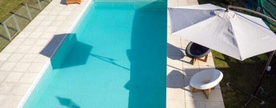 Piscina con sombrilla blanca y sillones de plástico